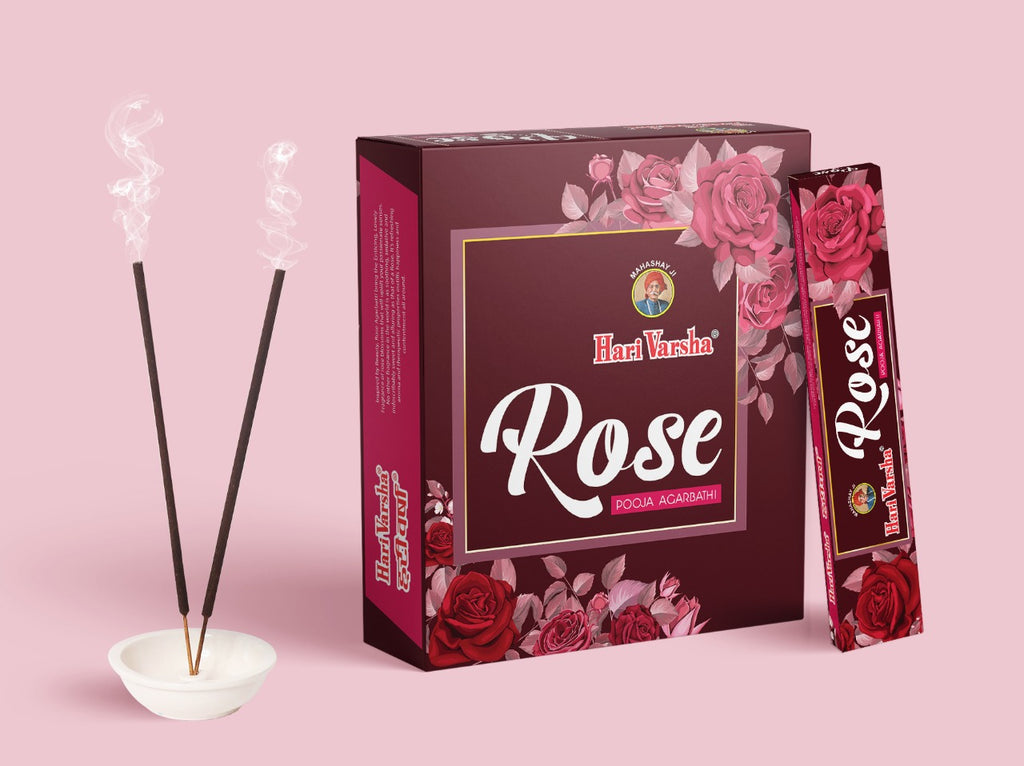 Hari Varsha Rose Pooja Agarbathi incense sticks burning in holder with product box and single pack on pink background